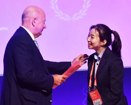 Susie Jo receiving an award from an IIHF official